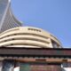 Stock market candlestick chart showing Sensex up with a strong green surge and traders monitoring screens
