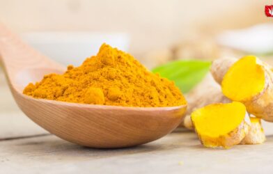 A bowl of turmeric powder with fresh turmeric roots placed beside it, highlighting the risks of excess turmeric consumption for kidney and liver health